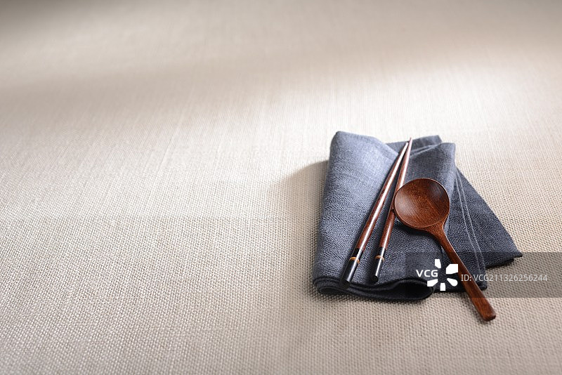 在麻布台布上的一套餐巾和传统的东方木制筷子和勺子图片素材