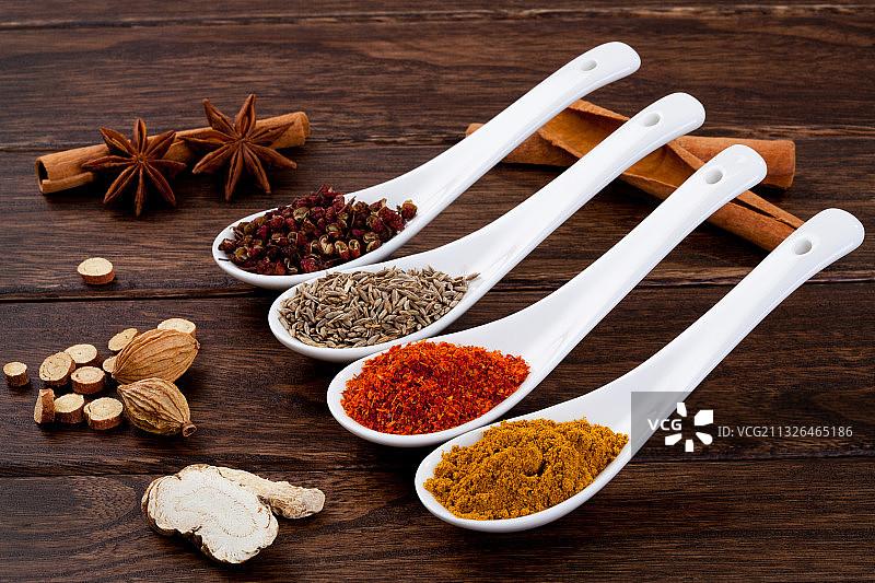 木桌上勺子里的各种调味料图片素材