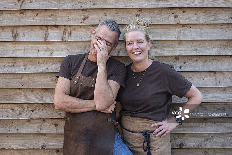 咖啡馆：英国，穿围裙的男女同事在工作休息时欢笑图片素材