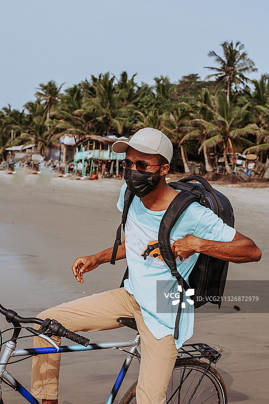 男子在加纳阿克拉海滩骑自行车的腰部特写图片素材