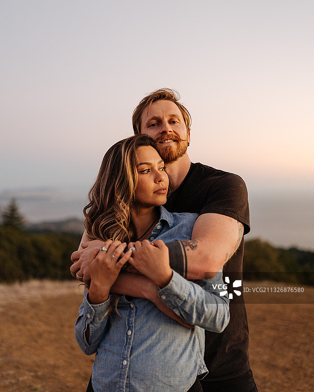 日落时拥抱的年轻情侣，塔玛佩莱斯山，美国加利福尼亚州图片素材