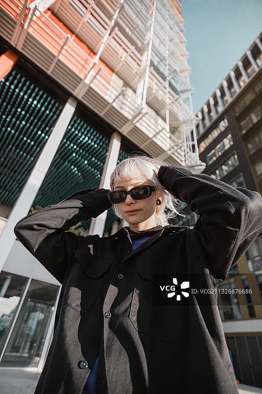在法国马赛，戴着太阳镜站在城市建筑物前的年轻女子肖像图片素材