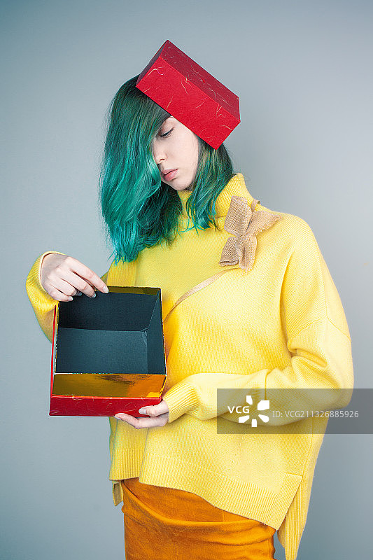 染着绿色头发，在灰色背景下穿黄色衣服的年轻女人图片素材