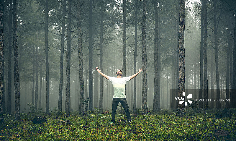 在阿根廷米西奥内斯蓝色山丘森林中张开双臂站立的男人图片素材