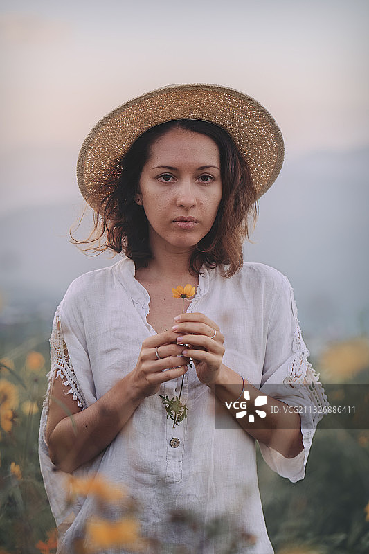 戴着草帽站在野花田里的女人图片素材