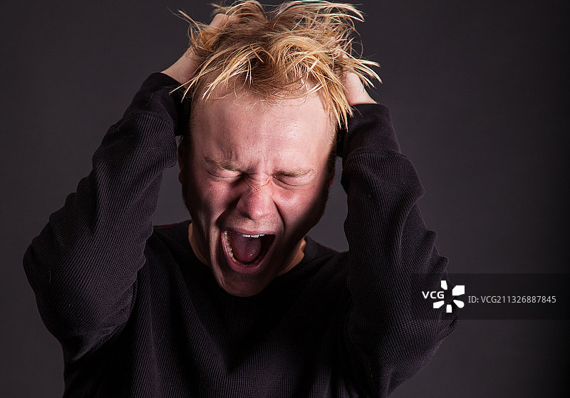 在黑色背景下哭泣的青年男子肖像图片素材