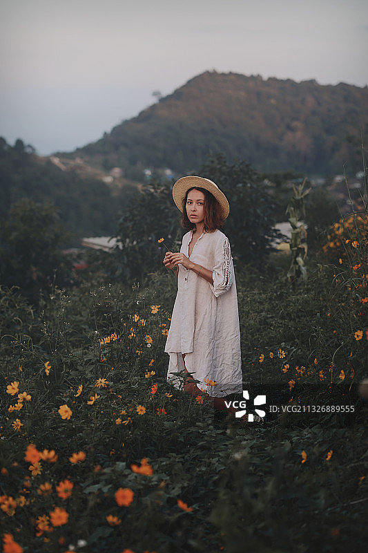 戴着草帽站在野花田里的女人图片素材