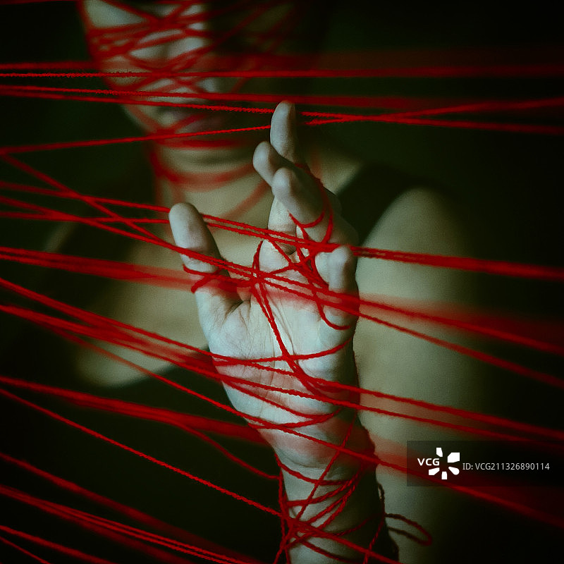 女人手部缠绕在红色细绳网中特写图片素材