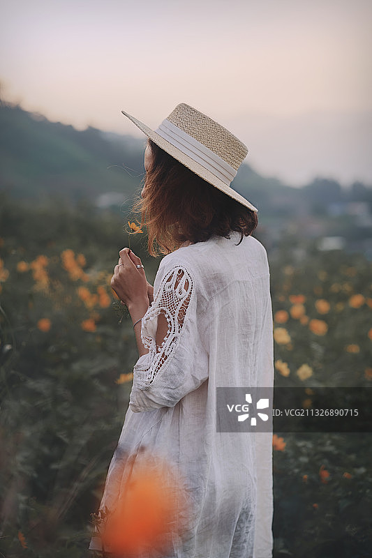 戴着草帽站在野花田里的女人图片素材