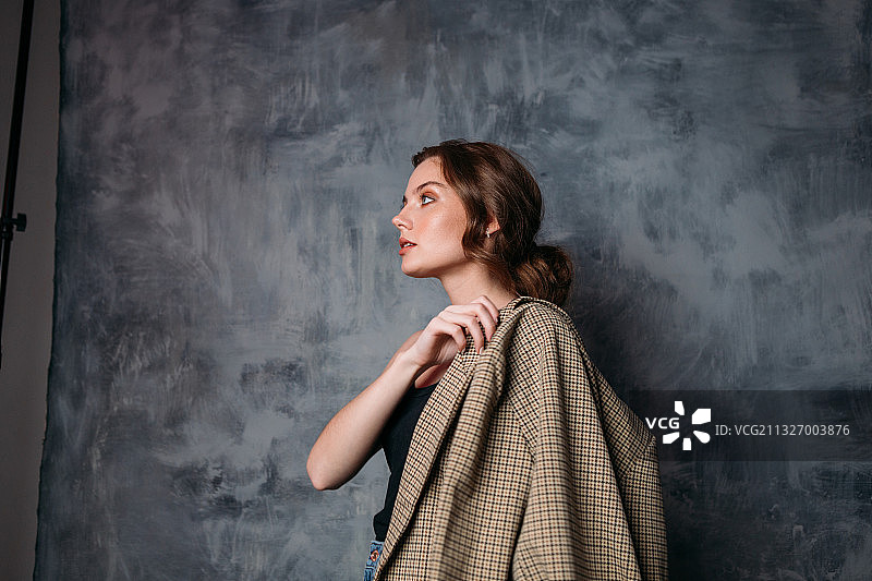 年轻女子在俄罗斯摄影棚灰色背景下身穿夹克图片素材