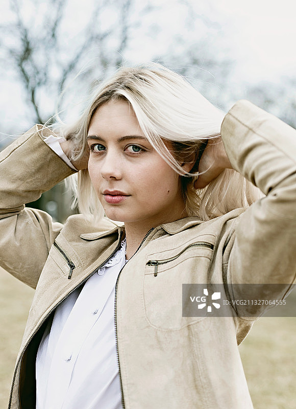 年轻女子在户外用手拨弄头发的肖像，美国威斯康星州密尔沃基图片素材