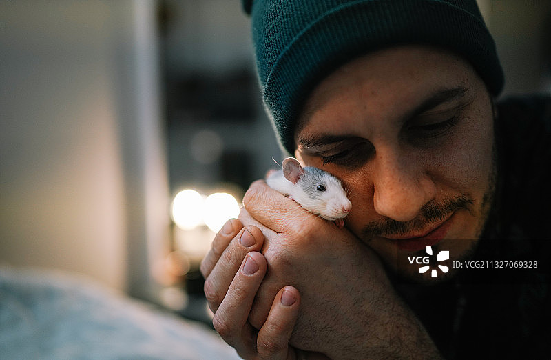 年轻男子在家与宠物鼠拥抱，西班牙莱里达图片素材