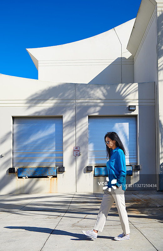 棕发女人穿着蓝色毛衣和白色裤子探索城市图片素材