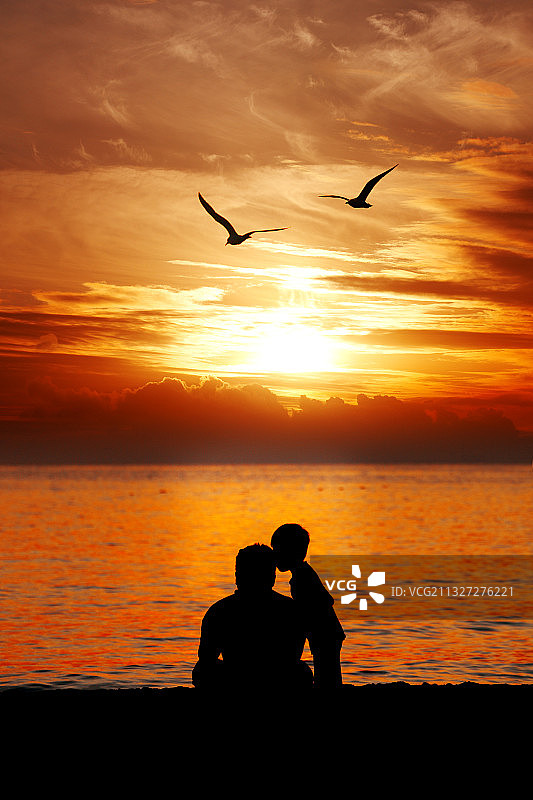 热浪岛的温馨日落，可爱的孩子和父亲的耳语图片素材