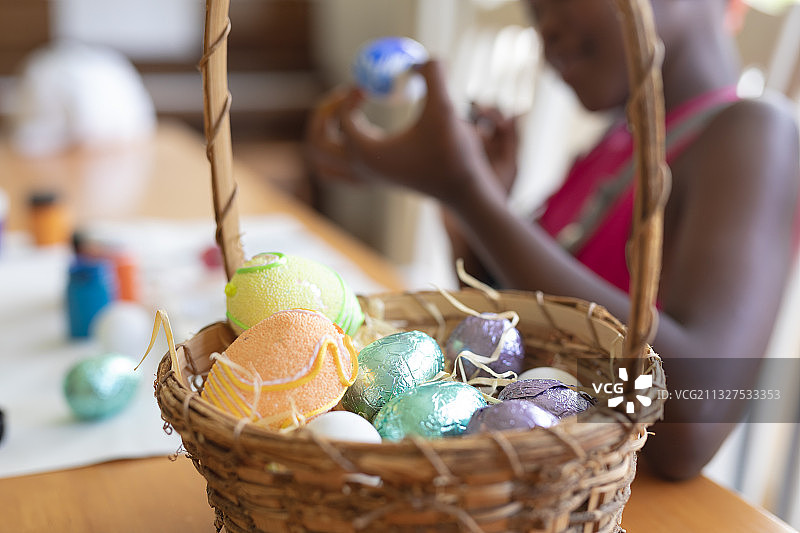 篮中彩色鸡蛋与背景画画的非洲裔女孩图片素材