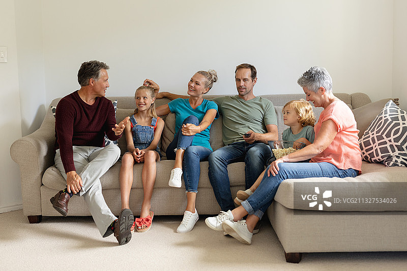 年长的白人男人坐在沙发上与三代家人交谈图片素材