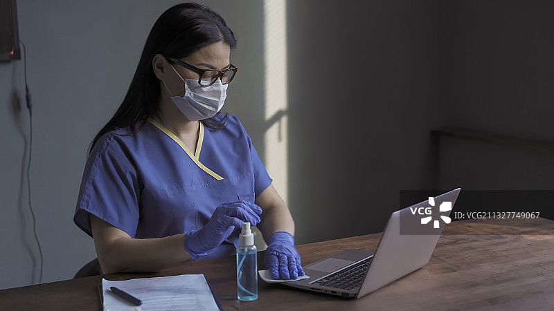 女医生在医院使用笔记本电脑并擦拭表面消毒图片素材