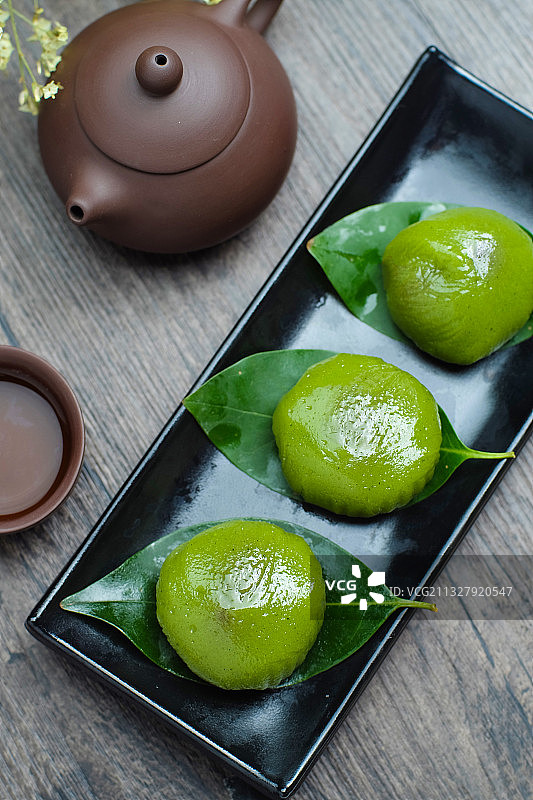 青团放在黑色盘子里和紫砂壶图片素材