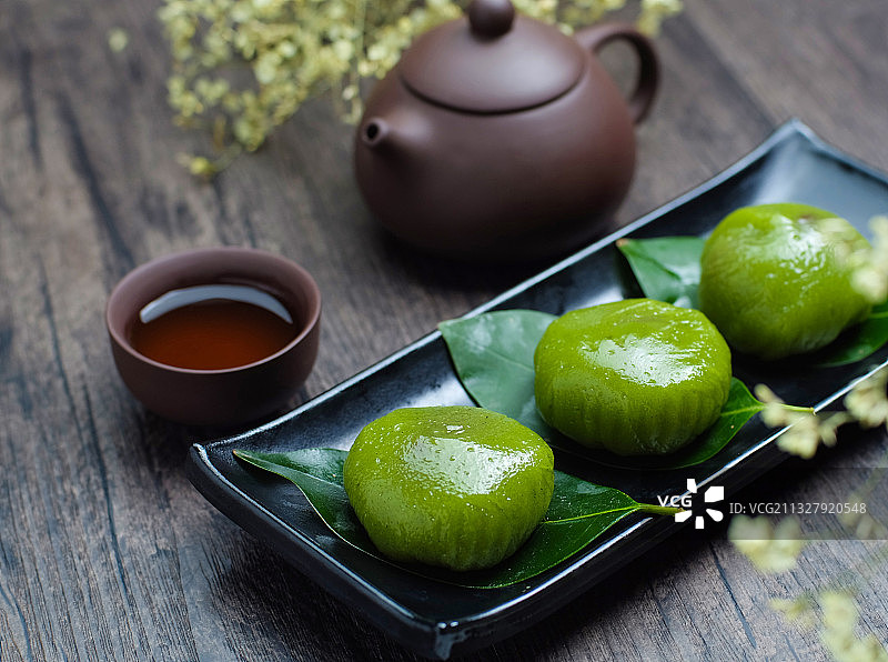 青团放在黑色盘子里和紫砂壶图片素材