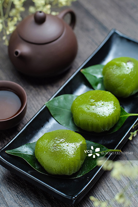 青团放在黑色盘子里和紫砂壶图片素材