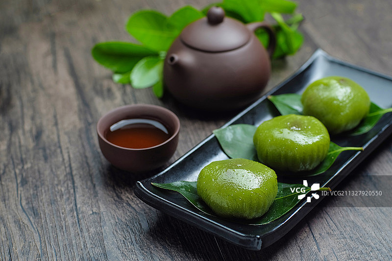 青团放在黑色盘子里和紫砂壶图片素材