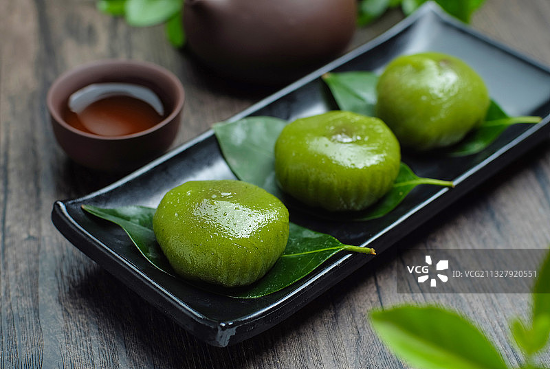 青团放在黑色盘子里和紫砂壶图片素材