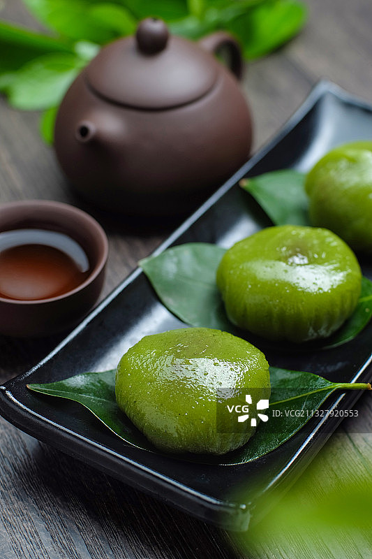 青团放在黑色盘子里和紫砂壶图片素材