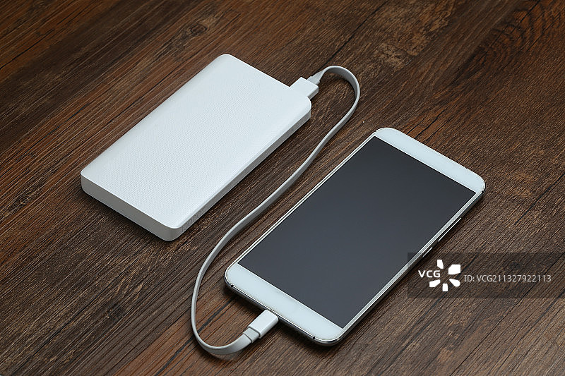 充电宝和智能手机放在木桌上图片素材