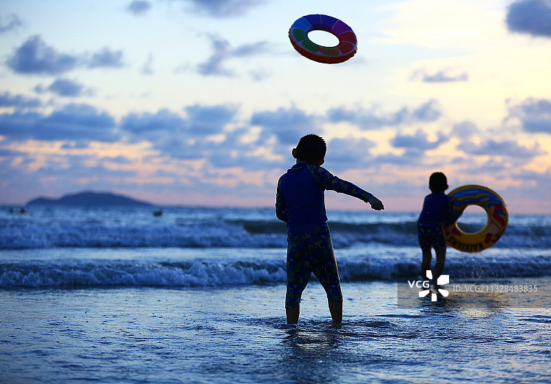 夏日的傍晚时分，2名小朋友在海南省三亚市三亚湾海边玩耍。图片素材