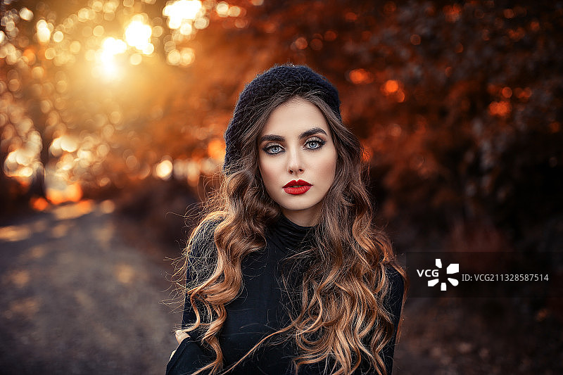 美丽的年轻女人在秋天站在树前的肖像图片素材