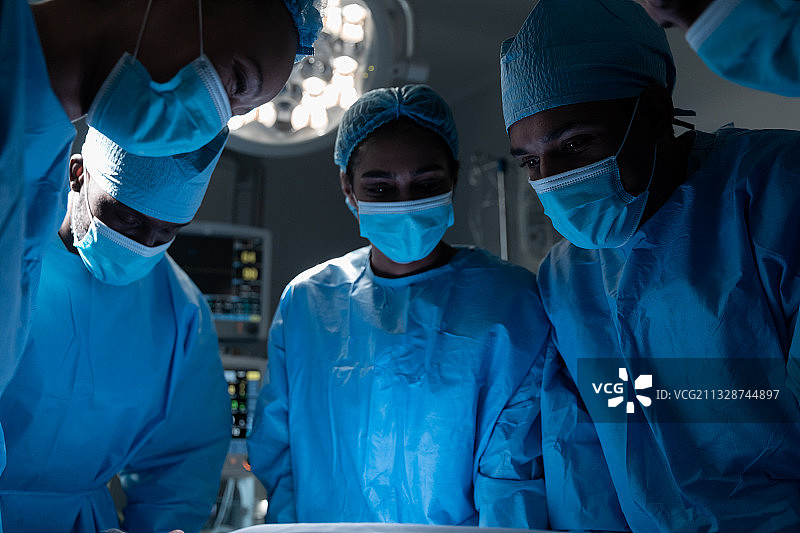 在医院做手术时戴着口罩和防护服的外科医生图片素材