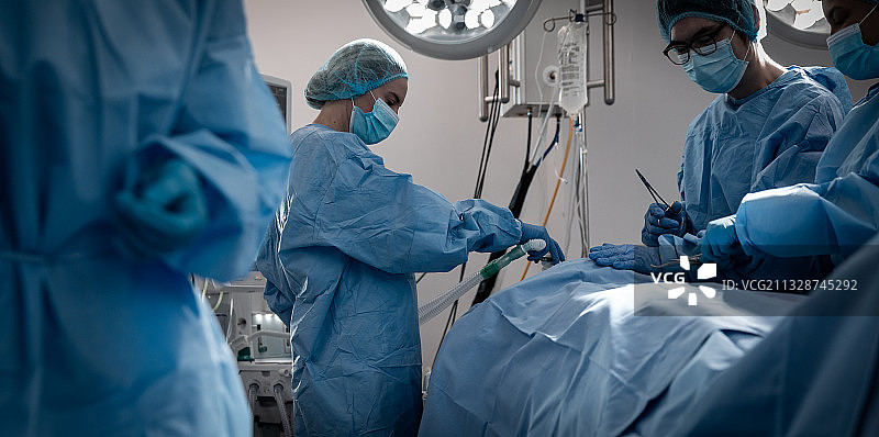 一群不同肤色的男女外科医生在手术室里戴着口罩做手术图片素材