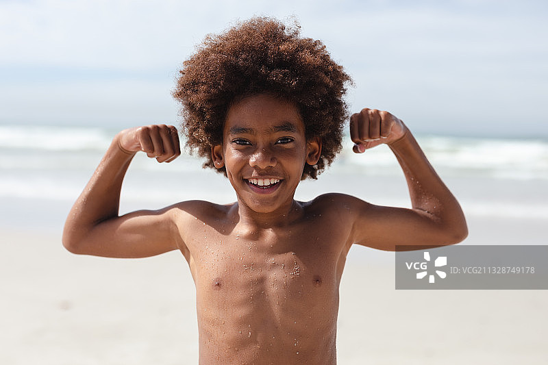 非洲裔男孩在海滩展示肱二头肌图片素材