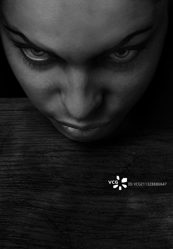 手托下巴坐在桌旁的悲伤女子肖像，适合书籍封面图片素材