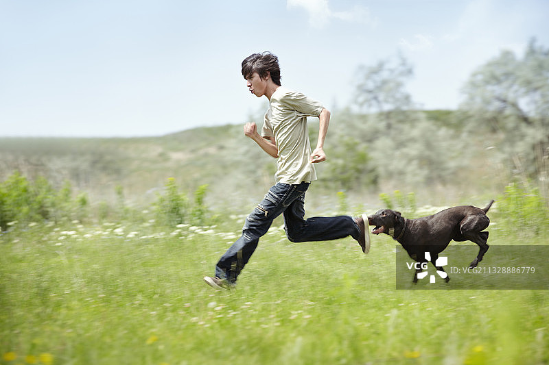 户外青年与狗奔跑，自然光色，动态虚化效果图片素材