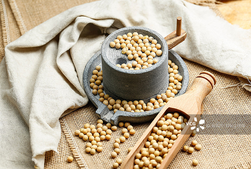 黄豆和小石磨放在麻布背景上图片素材