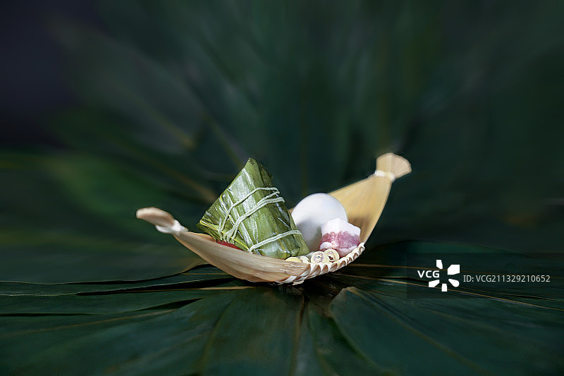 放在绿色粽叶里的船型竹篮和粽子图片素材