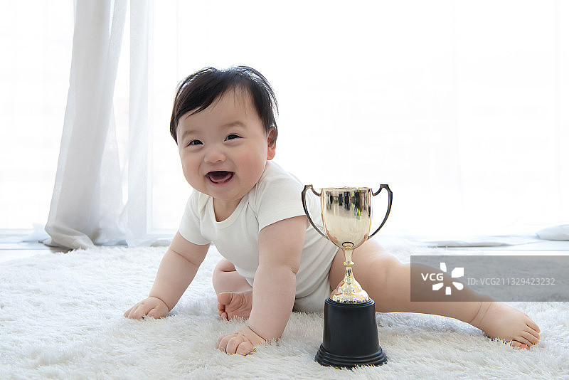 坐在奖杯后面的可爱微笑婴儿图片素材