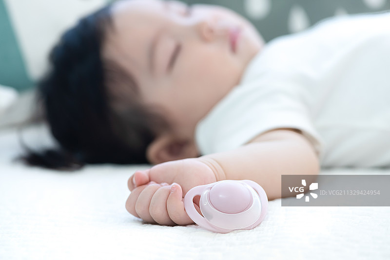 一个正在睡觉的婴儿和旁边的拨浪鼓图片素材