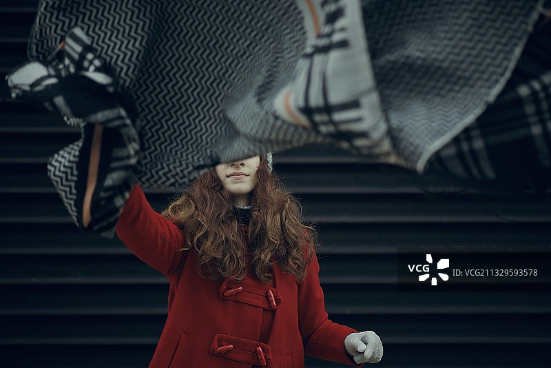 年轻女子手持围巾靠墙的肖像图片素材