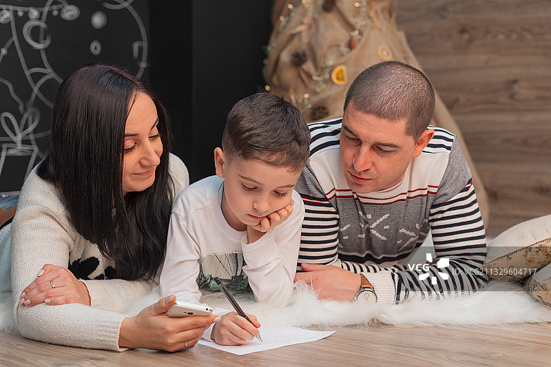 妈妈和爸爸与儿子一起给圣诞老人写信图片素材