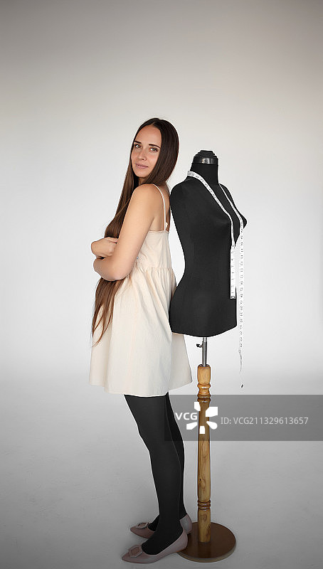 年轻漂亮的女裁缝和人体模型在她工作的地方图片素材