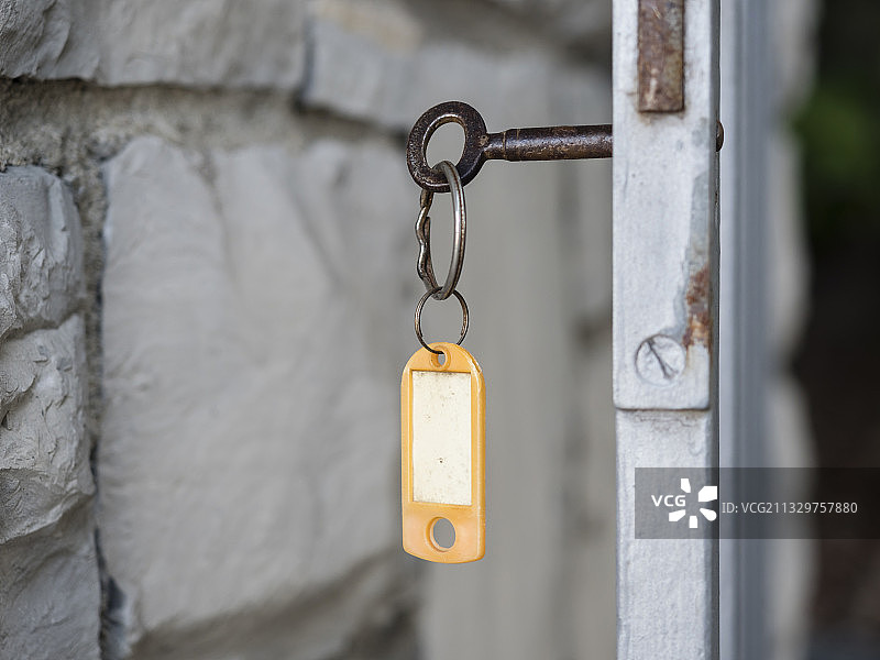 插入门锁的带钥匙圈和模糊标签的旧钥匙图片素材