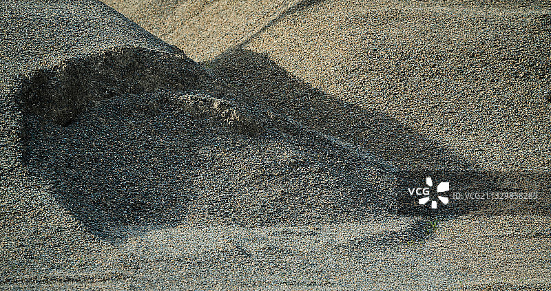 在夕阳的光影里，有着三角形和不规则阴影构图的沙堆。图片素材