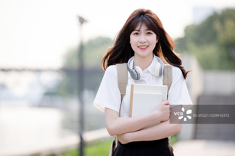 在户外，漂亮美丽的亚洲女大学生图片素材