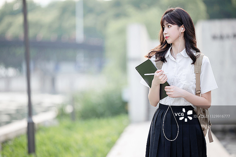 在户外，漂亮美丽的亚洲女大学生图片素材