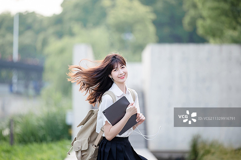 在户外，漂亮美丽的亚洲女大学生图片素材