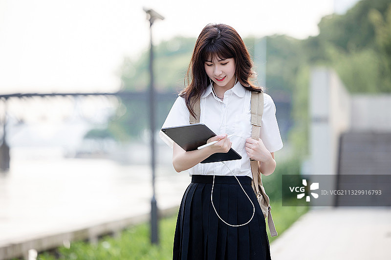 在户外，漂亮美丽的亚洲女大学生图片素材