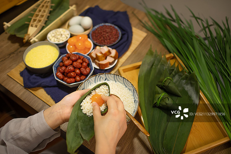 亚洲家庭主妇在包咸蛋黄粽子图片素材