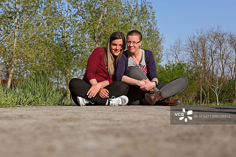 微笑的朋友们坐在树木旁的路上，塞尔维亚库尔平图片素材